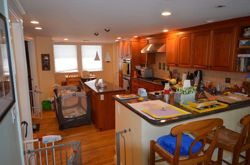 Bright kitchen with wooden cabinets, toddler play area, and organized dining space.